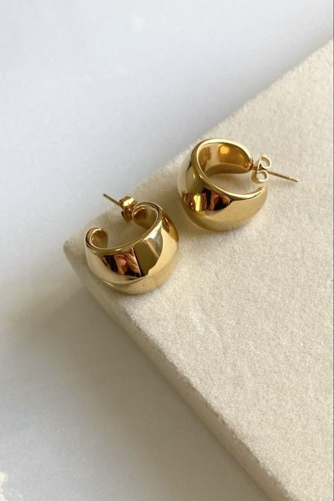 Gold earrings showcased on a foam